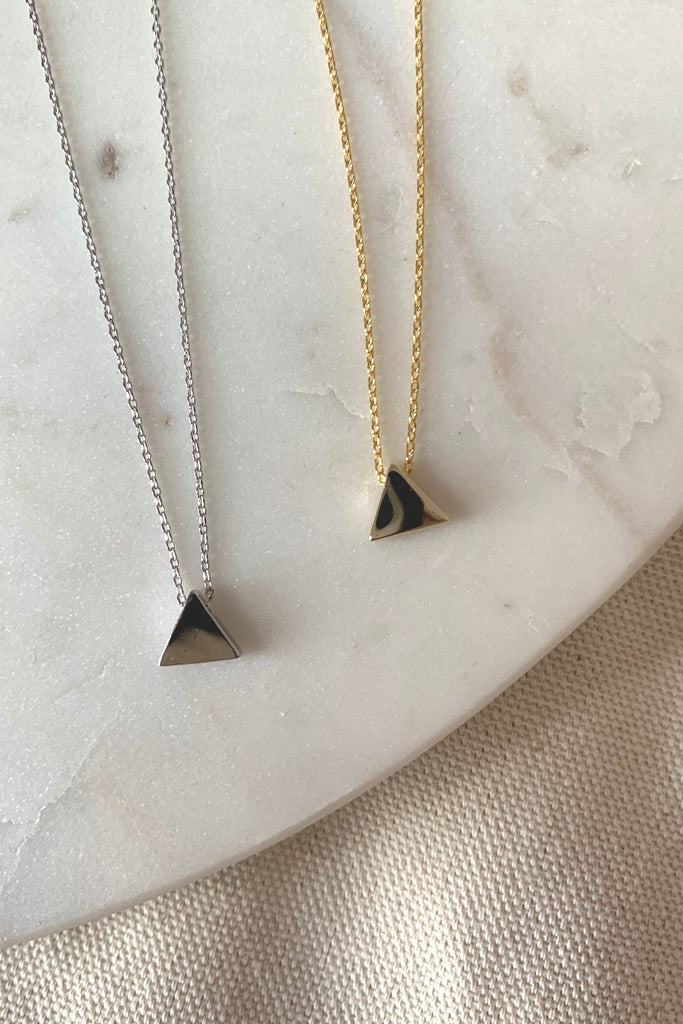 Look unique and stylish with this dainty triangle charm necklace. It's gold-dipped and comes in gold and silver, perfect for those looking for a modern yet timeless accessory. Make a statement with a simple but eye-catching piece.