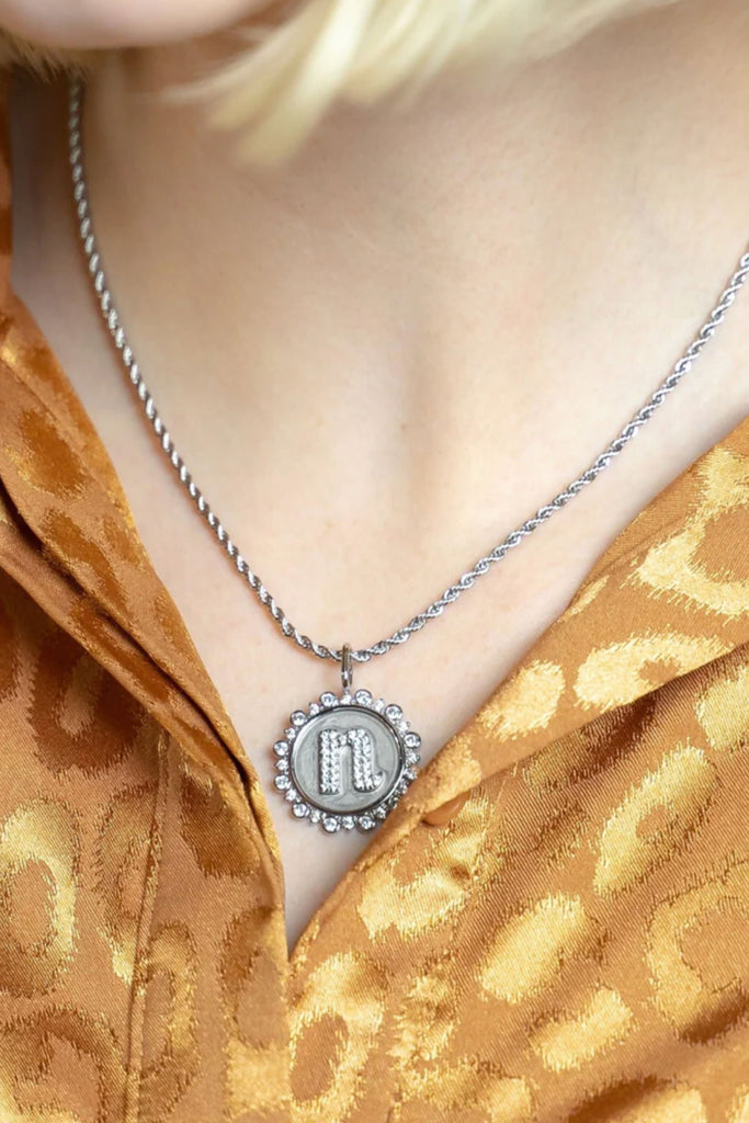 Choose your favorite chain and charms! The Sis Kiss coin initial pendant is vintage inspired and accented with crystals. It's the perfect silver statement jewelry piece and a fun way to customize your look. 