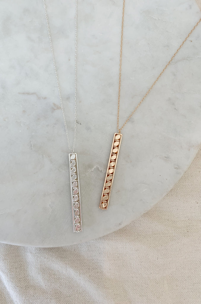 Make a statement with our 30" Beaded Bar Necklace. Perfectly crafted with stunning beaded details, this statement necklace is sure to complete any outfit. It has a 30" chain with a long rectangle bar shaped pendant. The pendant has a beaded circle design. Choose between gold or silver to match back to your other jewelry! 