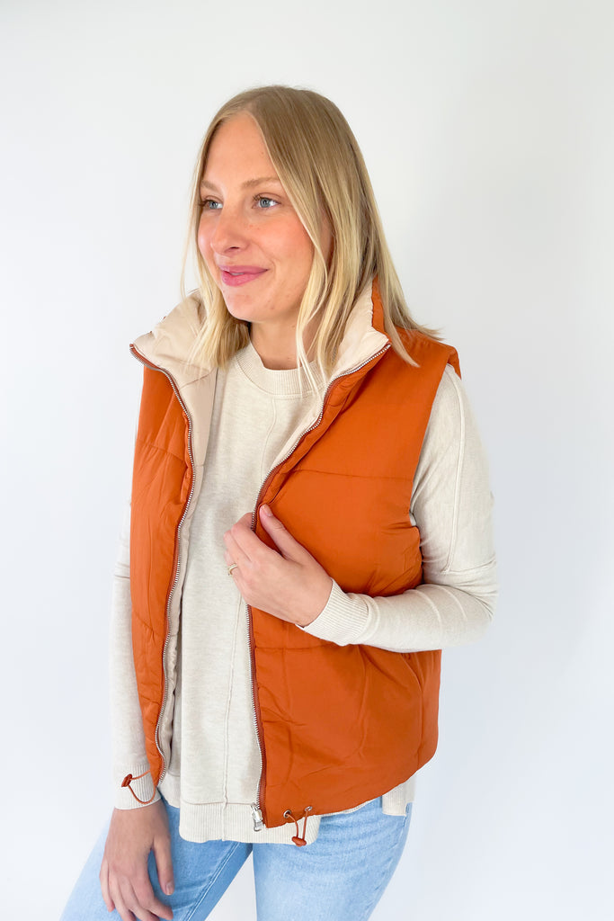 This stylish Beige + Orange Reversible Puff Vest is a great way to stay warm without sacrificing your sense of style. It comes in a beige and orange color that's eye-catching. It features a zip-up front, side pockets, and an adjustable drawstring at the bottom for a perfect fit.