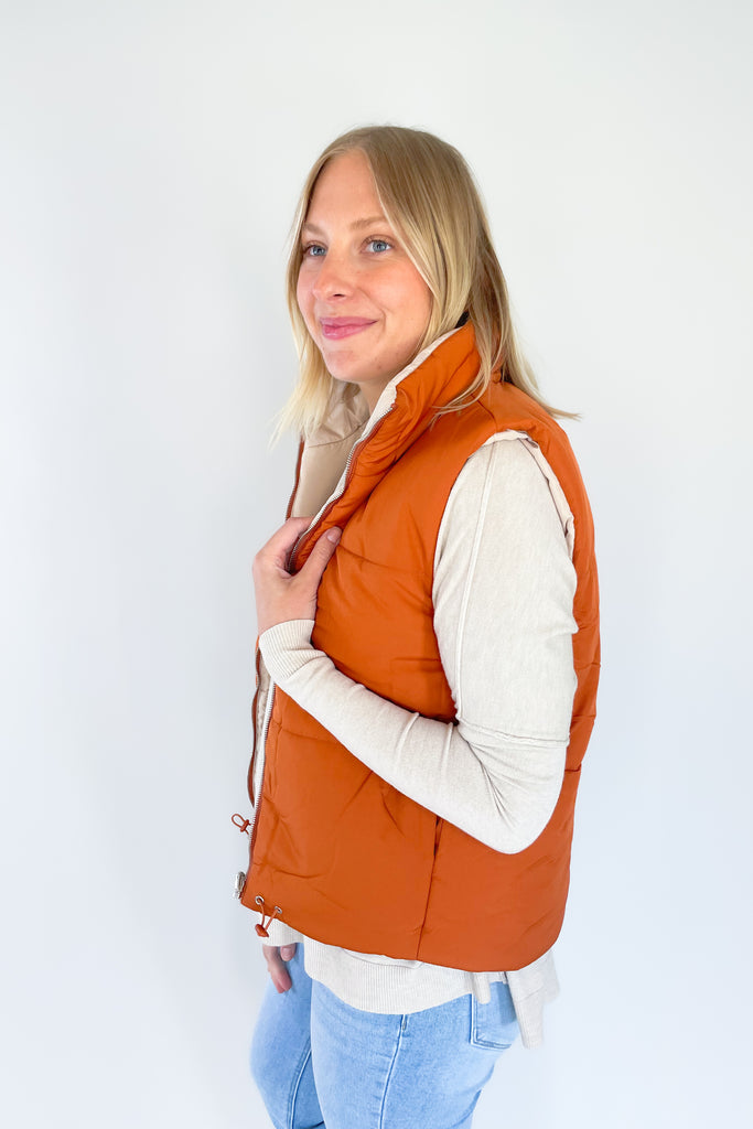 This stylish Beige + Orange Reversible Puff Vest is a great way to stay warm without sacrificing your sense of style. It comes in a beige and orange color that's eye-catching. It features a zip-up front, side pockets, and an adjustable drawstring at the bottom for a perfect fit.