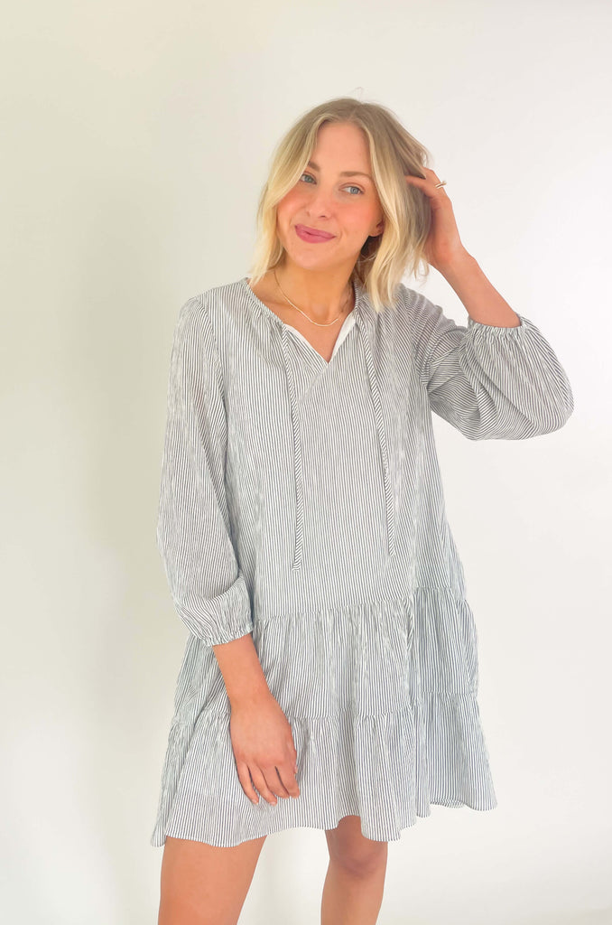 Freshen up your wardrobe with the black and white stripe By the Bay Tiered Dress! Featuring a lightweight fabric, long sleeves, side pockets and tassel ties, this timeless look is a fashionable must-have! 