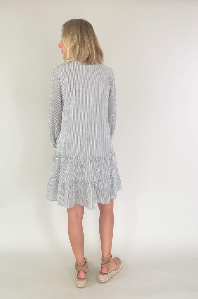 Freshen up your wardrobe with the black and white stripe By the Bay Tiered Dress! Featuring a lightweight fabric, long sleeves, side pockets and tassel ties, this timeless look is a fashionable must-have! 