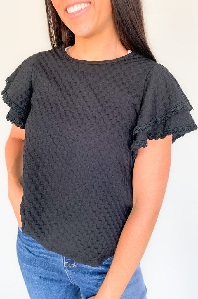  Our Daily Double Ruffle Textured Short Sleeve Blouse adds a chic touch to any wardrobe. Enjoy a sweet ruffle sleeve, a delicate lace trim on the ruffles, and a modern checkered pattern to give this blouse an elegant look! Perfect to be worn alone or under a blazer for a more formal look! 