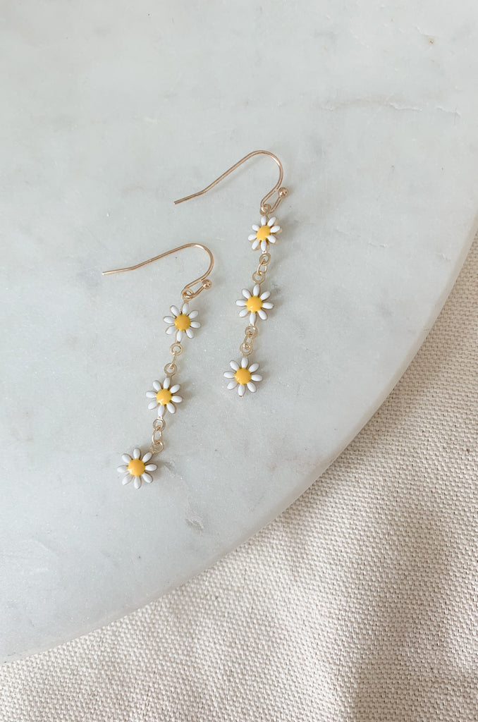 These ultra-dainty daisy enamel drop earrings will surely be the bee's knees of any outfit this season. They are cute, colorful, and very comfortable! Each enamel daisy is linked by a gold chain with a hook backing. 