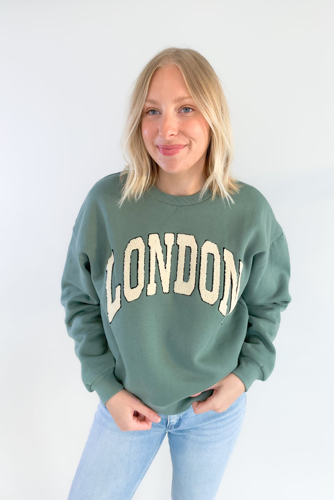 Stay comfortable and stylish with the Emerald London Graphic Pullover! This pullover has a relaxed fit and features a unique textured lettering in a light ivory. The lettering has a fun contrast. It's slightly oversized with a soft, stretchy fabric. The inside is fleece lined. You cannot go wrong with this one! 