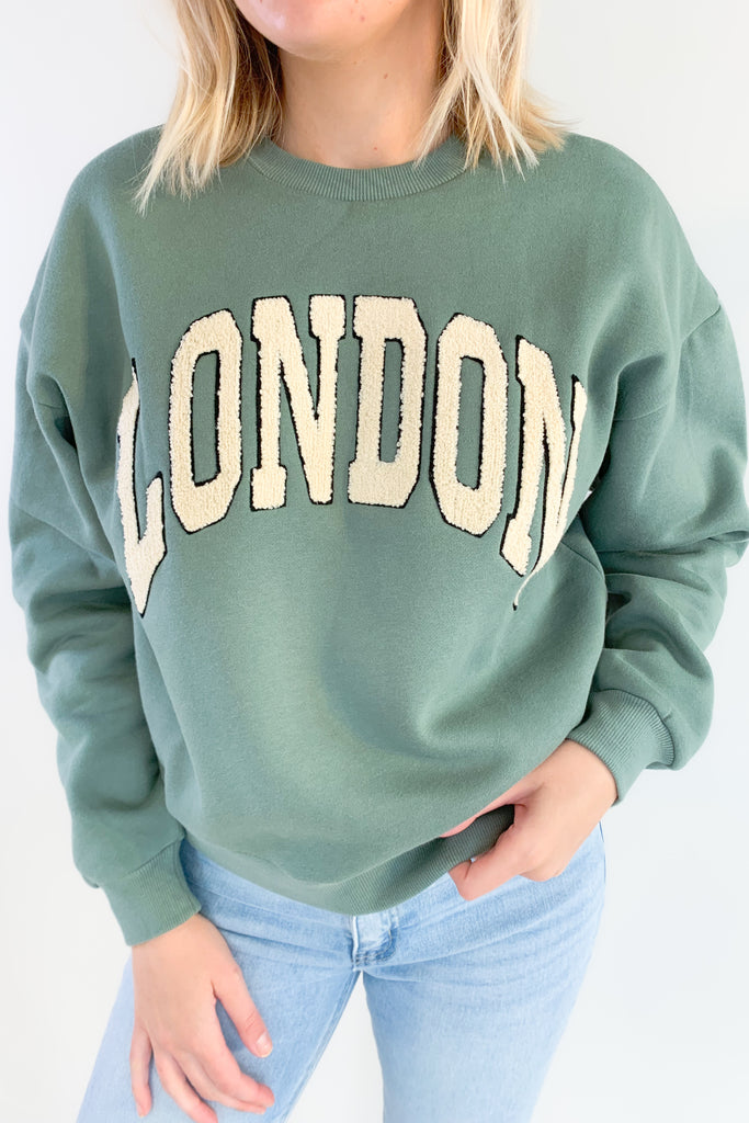 Stay comfortable and stylish with the Emerald London Graphic Pullover! This pullover has a relaxed fit and features a unique textured lettering in a light ivory. The lettering has a fun contrast. It's slightly oversized with a soft, stretchy fabric. The inside is fleece lined. You cannot go wrong with this one! 