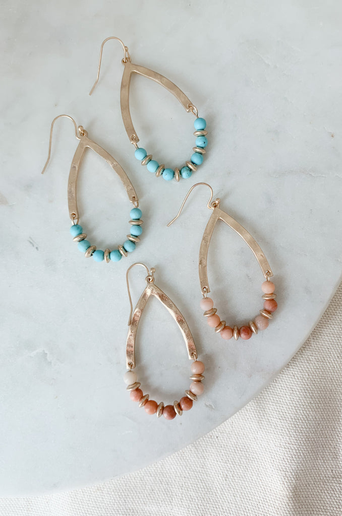 Be the trendsetter with these beautiful Hammered Teardrop Earrings! They add a touch of uniqueness to any look with the beaded details. Available in two shimmery, eye-catching color combos: peach and gold, or turquoise and gold.