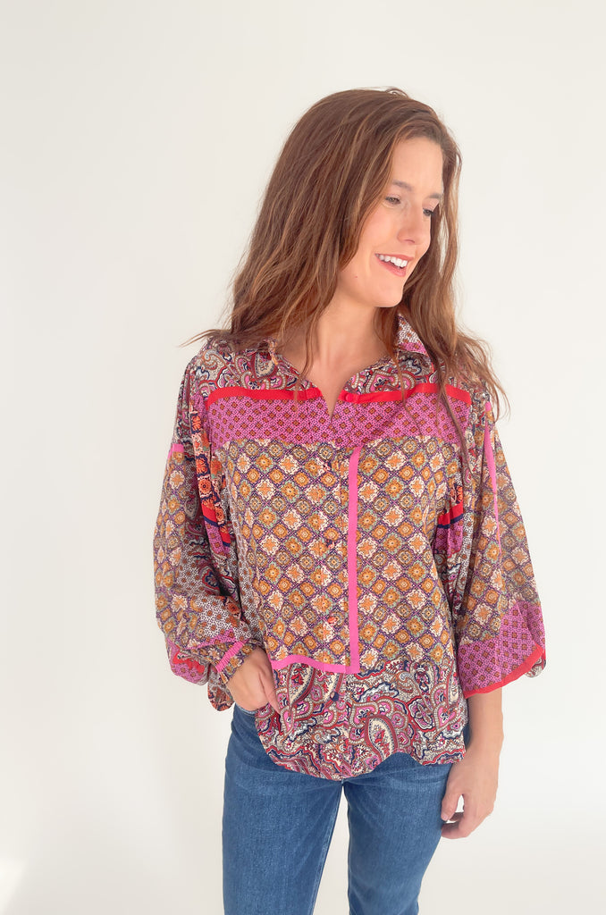 This Hot Pink & Red Boho Long Sleeve Blouse has a lightweight sheer material and features a stylish collar and cinched wrists for a sleek work look! The stylish print features pops of red, magenta, mustard, and green.