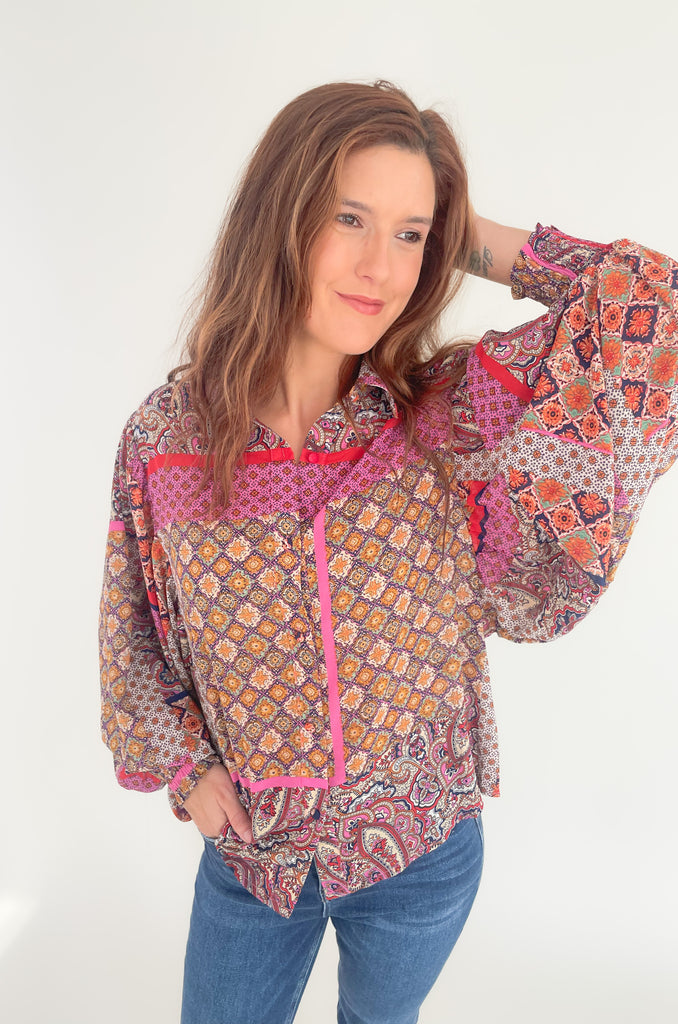 This Hot Pink & Red Boho Long Sleeve Blouse has a lightweight sheer material and features a stylish collar and cinched wrists for a sleek work look! The stylish print features pops of red, magenta, mustard, and green.