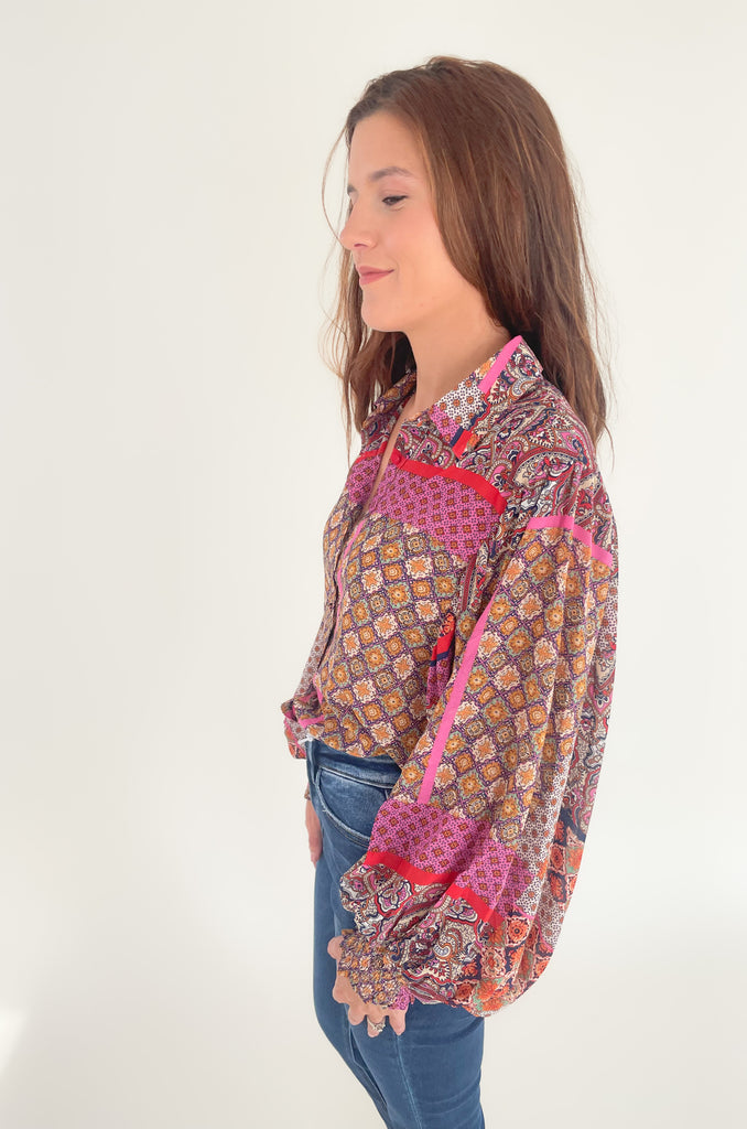 This Hot Pink & Red Boho Long Sleeve Blouse has a lightweight sheer material and features a stylish collar and cinched wrists for a sleek work look! The stylish print features pops of red, magenta, mustard, and green.