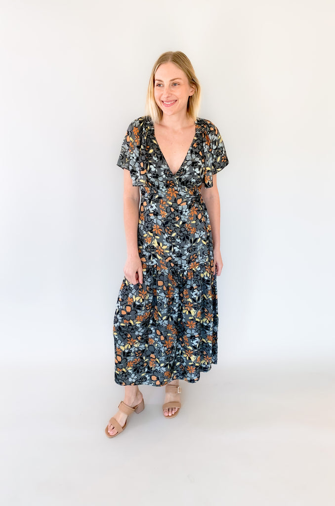 Maxi dress with a v-neckline. With a wrap dress that ties and has a beautiful floral print with gray, orange, light blue, and yellow coloring!