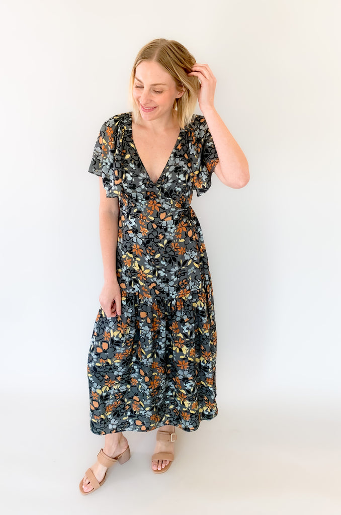 Maxi dress with a v-neckline. With a wrap dress that ties and has a beautiful floral print with gray, orange, light blue, and yellow coloring!