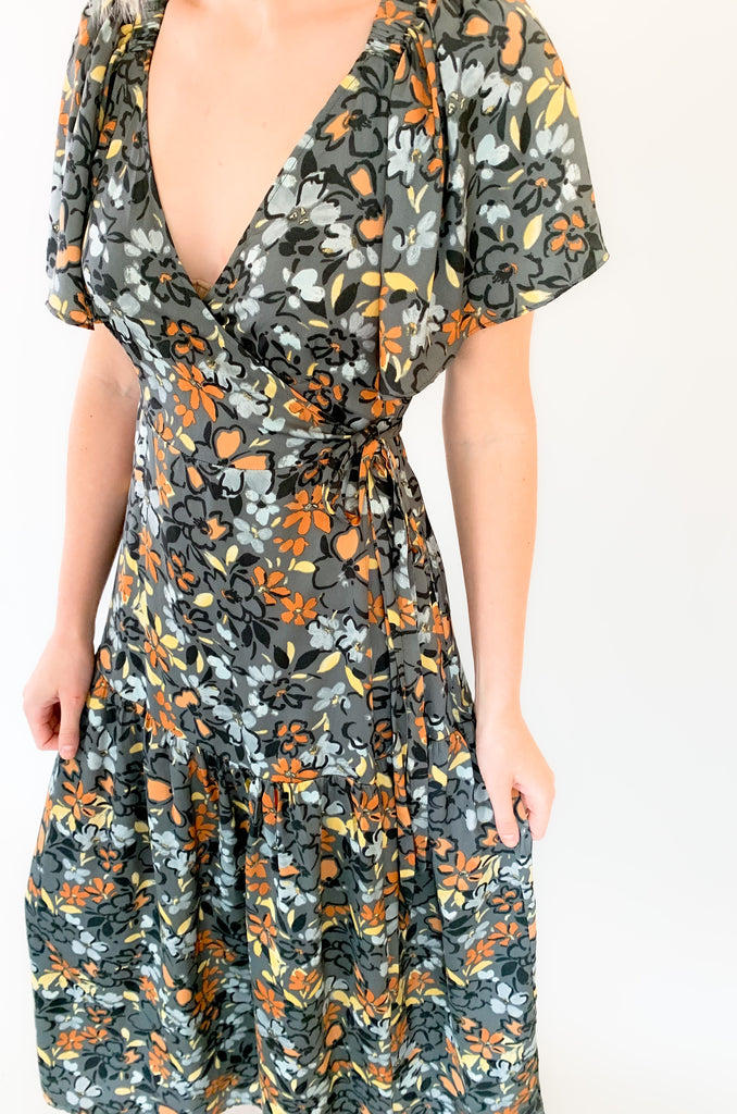 Maxi dress with a v-neckline. With a wrap dress that ties and has a beautiful floral print with gray, orange, light blue, and yellow coloring!