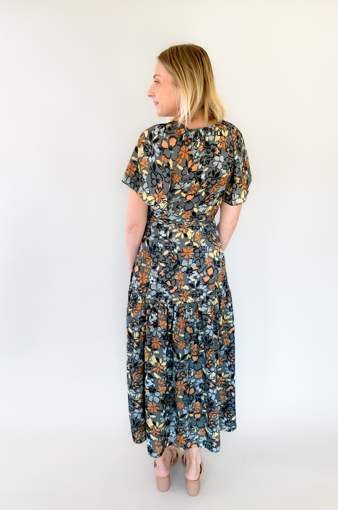 Maxi dress with a v-neckline. With a wrap dress that ties and has a beautiful floral print with gray, orange, light blue, and yellow coloring!