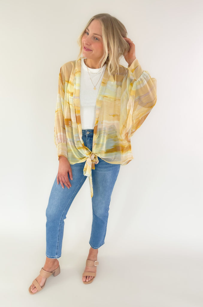 Brighten up your closet with the Madrid Relaxed Kimono. This stylish piece features a beautiful yellow, peach, and white watercolor print, balloon sleeves, and a flattering adjustable tie in the front. It's perfect for adding a splash of color to any outfit.