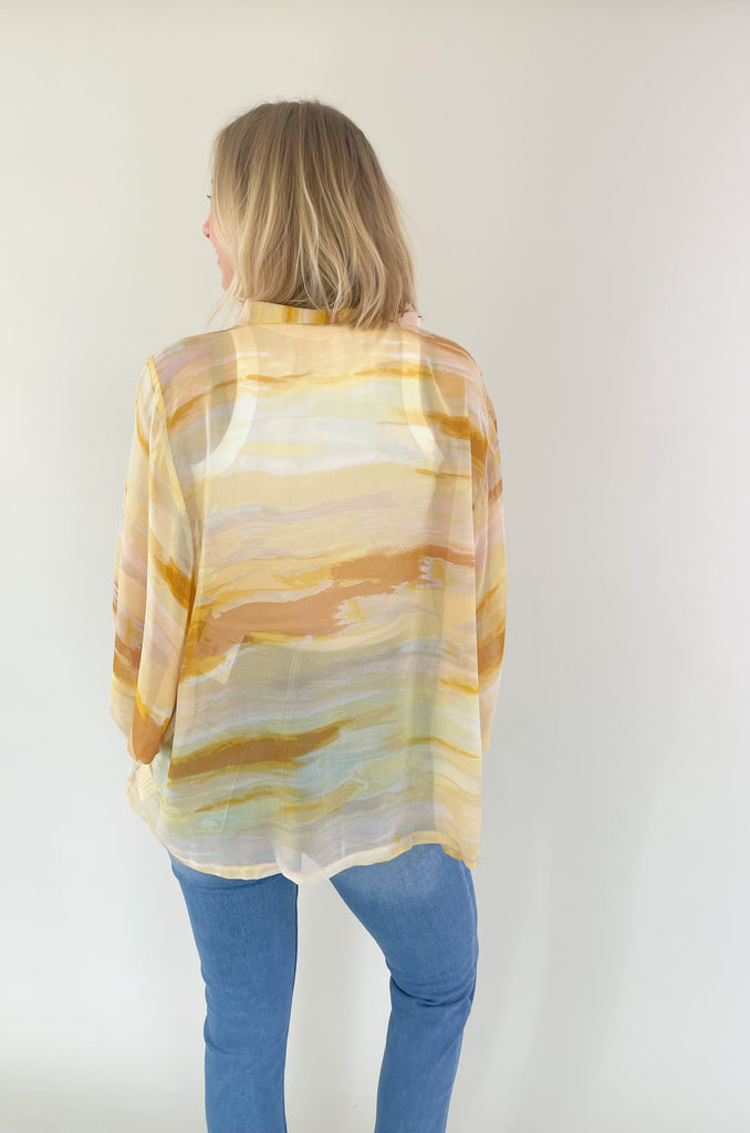 Brighten up your closet with the Madrid Relaxed Kimono. This stylish piece features a beautiful yellow, peach, and white watercolor print, balloon sleeves, and a flattering adjustable tie in the front. It's perfect for adding a splash of color to any outfit.
