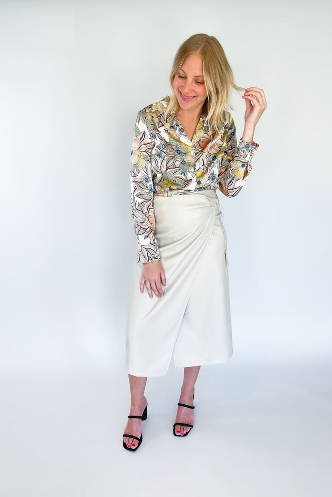 The Sandi Wrap Midi Skirt is a must-have for any fashion lover. It's no secret that skirts are taking the world by storm, especially midi styles like this one. It's crafted from a beige faux leather with a soft fabric lining. The soft inside ensures comfort, while the tassel ties and flattering fit add a stylish touch.