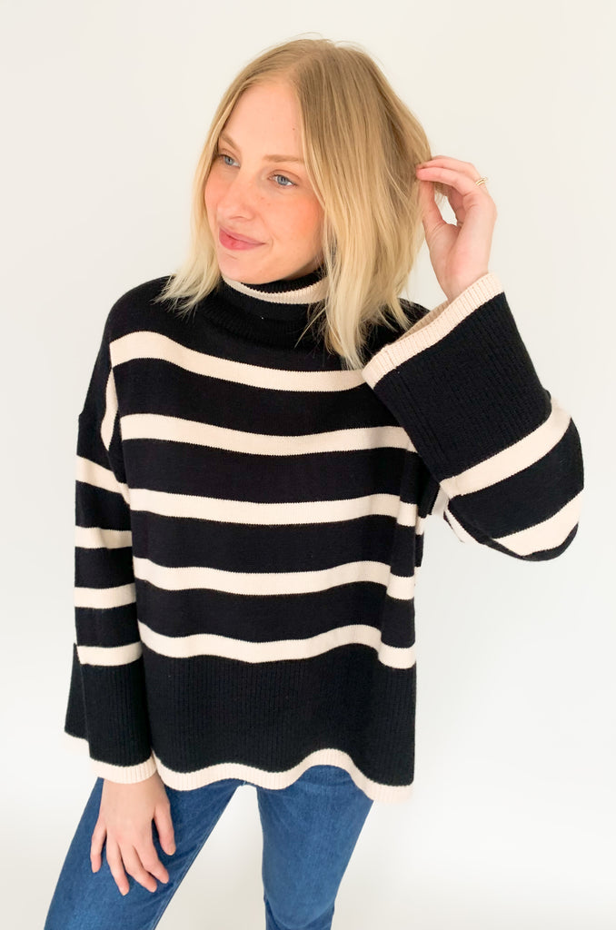 Striped pink or black turtleneck with wide sleeves, flowy body, and side slits in a comfortable knit fabric