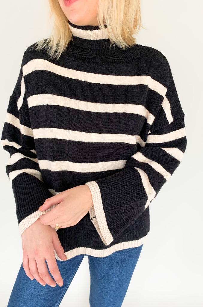 Striped pink or black turtleneck with wide sleeves, flowy body, and side slits in a comfortable knit fabric