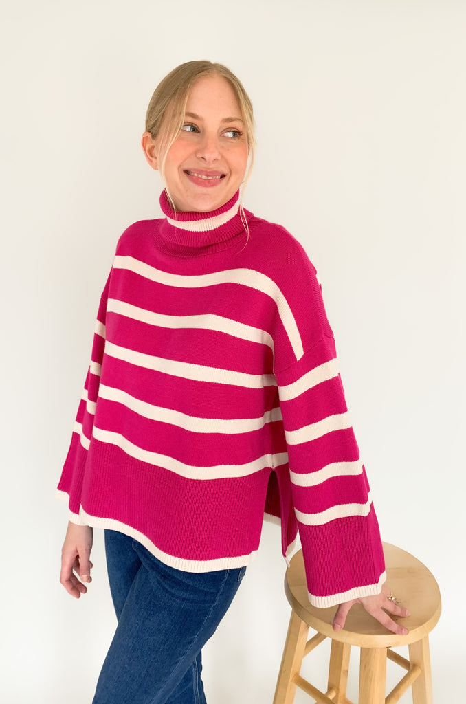 Striped pink or black turtleneck with wide sleeves, flowy body, and side slits in a comfortable knit fabric