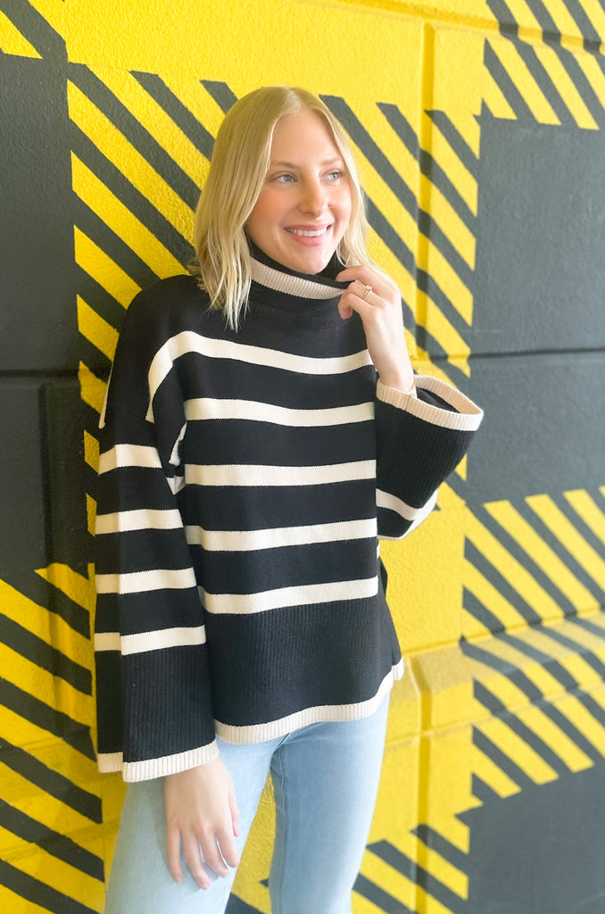 Striped pink or black turtleneck with wide sleeves, flowy body, and side slits in a comfortable knit fabric