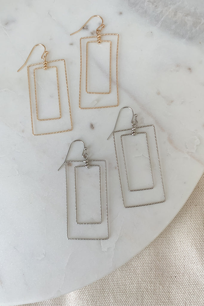 These Sparkle Double Rectangle Wire Earrings offer an eye-catching and unique design. The statement pieces feature two layers of sparkly wire frames, giving them an elegant and contemporary look. Intricately crafted and lightweight, these earrings are perfect for any occasion.