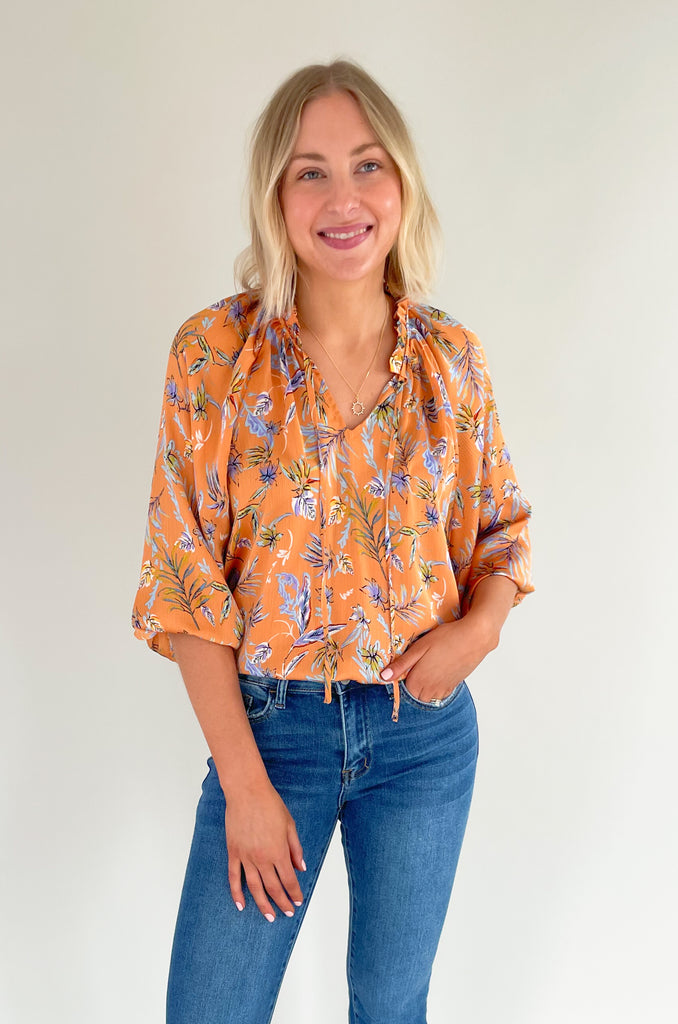 Look your best this summer with our new Tully Floral Blouse! It's elevated and bright with a blue and green floral leaf print. Featuring a ruffle neckline and tassel ties, this blouse creates an eye-catching look