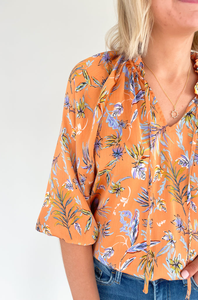 Look your best this summer with our new Tully Floral Blouse! It's elevated and bright with a blue and green floral leaf print. Featuring a ruffle neckline and tassel ties, this blouse creates an eye-catching look