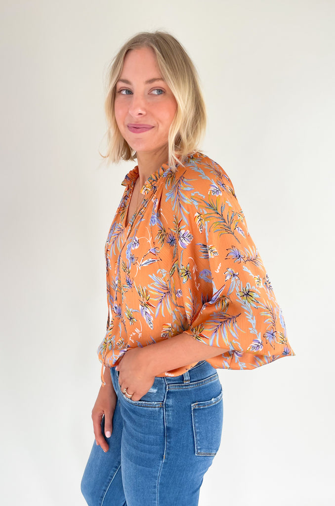 Look your best this summer with our new Tully Floral Blouse! It's elevated and bright with a blue and green floral leaf print. Featuring a ruffle neckline and tassel ties, this blouse creates an eye-catching look