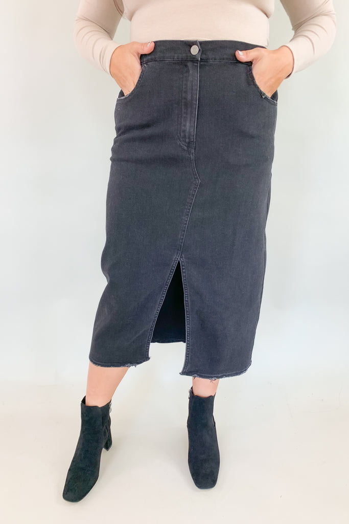 The Vintage Wash Black Denim Midi Skirt is super trendy, but very comfortable for an all denim skirt. The elastic back and lighter weight fabric makes this skirt a go-to for fall! We love the washed black color, front slit, and raw hem, giving this style an edgy look. 