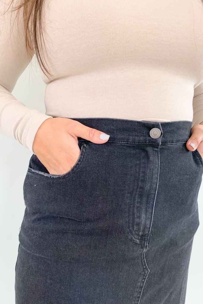 The Vintage Wash Black Denim Midi Skirt is super trendy, but very comfortable for an all denim skirt. The elastic back and lighter weight fabric makes this skirt a go-to for fall! We love the washed black color, front slit, and raw hem, giving this style an edgy look. 