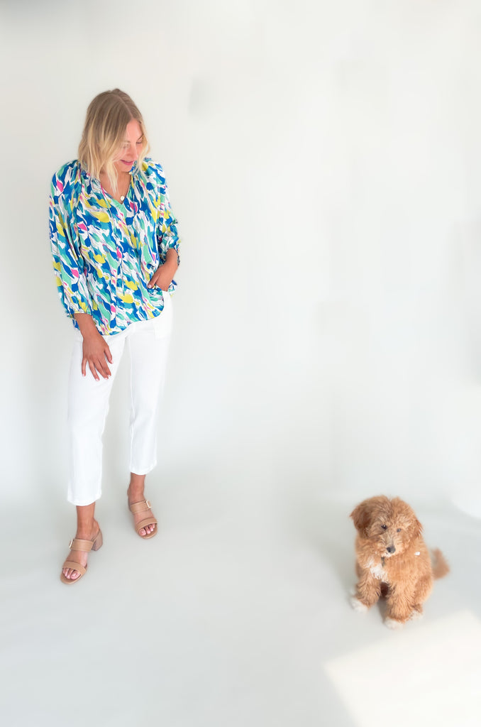 Long sleeve blouse with pops of vibrant blues, yellow, and pinks, flowy with balloon sleeve, lightweight silky feel, V-neck with a tie detailing and pleated neckline