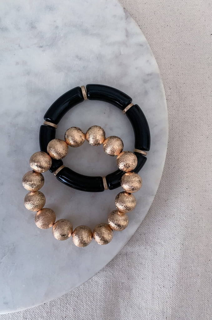 The 2 Stack Bead & Gold Bracelets are such a fun and trendy way to elevate any outfit. Wear it to work, a night out, or for a special event. This two bracelet set has one that is black beaded and the other gold beaded. The contrast really makes a statement! This chunky stretch bracelet is going to be an essential for every closet!