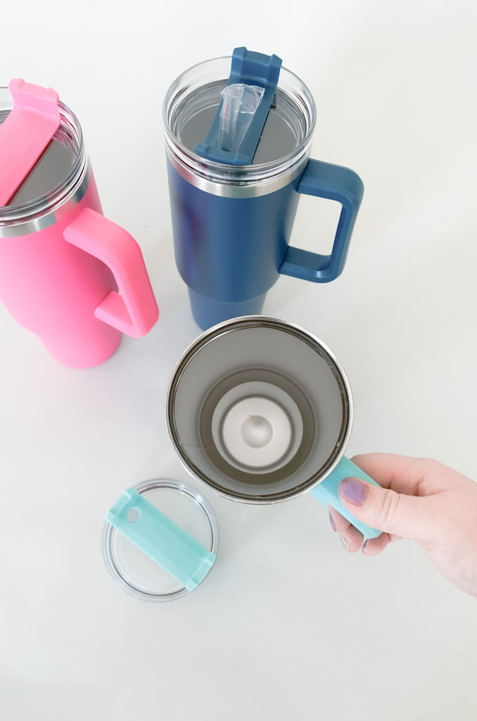 The 40oz Stainless Steel Travel Tumbler is the perfect on-the-go accessory to keep your drinks cold all day long! It's a large size with a comfortable grip handle. The bottom is tapered to fit into your car cup holders. Each bottle comes with a screw on top and plastic straw. Choose between Navy, Aqua, and Hot Pink! Stanley mug dupe