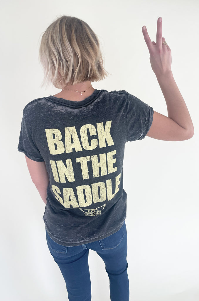 The Aerosmith Back In The Saddle Tee is so comfortable it doesn't even matter how fun it is! But if you love a good band tee, this style is one of the best! It has a cool Aerosmith leopard print graphic on the front and "Back in the Saddle" on the back. Graphic tees are the perfect, cool girl look that's right on trend this season. You will be reaching for it every time you go out, go to a concert, or want to play up your outfit. Try pairing it with our Upgrade Faux Suede Jacket for an easy layering option.