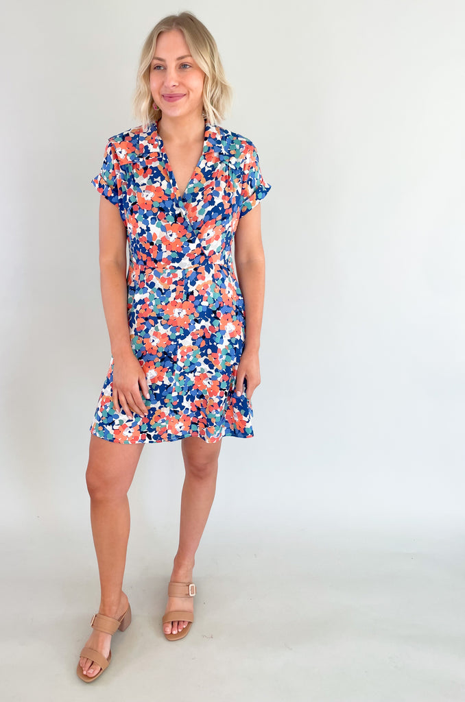 This stunning blue and coral floral print mini dress is designed to make you feel feminine, stylish, and confident. This dress features a flattering V-neckline that and wrap silhouette. It drapes beautifully over your body, creating a flattering and flowy fit. It has a collar detail, pleating around the neckline too. Plus, the colors are just so fun!