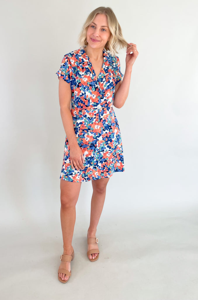 This stunning blue and coral floral print mini dress is designed to make you feel feminine, stylish, and confident. This dress features a flattering V-neckline that and wrap silhouette. It drapes beautifully over your body, creating a flattering and flowy fit. It has a collar detail, pleating around the neckline too. Plus, the colors are just so fun!