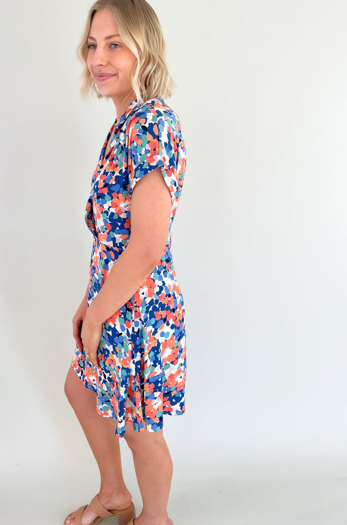 This stunning blue and coral floral print mini dress is designed to make you feel feminine, stylish, and confident. This dress features a flattering V-neckline that and wrap silhouette. It drapes beautifully over your body, creating a flattering and flowy fit. It has a collar detail, pleating around the neckline too. Plus, the colors are just so fun!