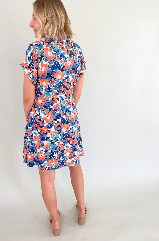 This stunning blue and coral floral print mini dress is designed to make you feel feminine, stylish, and confident. This dress features a flattering V-neckline that and wrap silhouette. It drapes beautifully over your body, creating a flattering and flowy fit. It has a collar detail, pleating around the neckline too. Plus, the colors are just so fun!