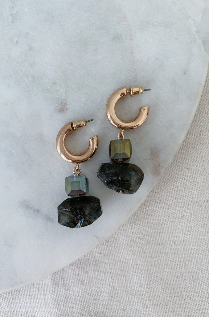 The Mini Hoop and Stone Dangle Earrings are a fun statement piece! Rich green tones cover the geometric bead and organic shaped stone. These dangle elements are connected to a gold hoop. They are so pretty and will instantly elevate your look. The Mini Hoop and Stone Dangle Earrings are a fun statement piece! Rich green tones cover the geometric bead and organic shaped stone. These dangle elements are connected to a gold hoop. They are so pretty and will instantly elevate your look. 