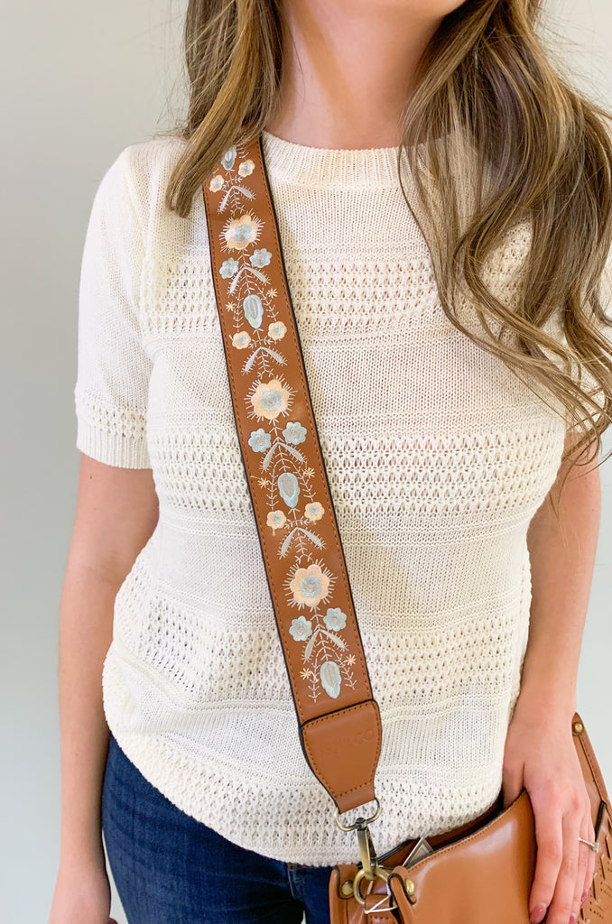The Pippa Crossbody Bag is a fun style with tons of details. It's made with a soft, satin-like faux leather. On the front pocket, there is a laser cutout design that creates a unique boho look. Each bag comes with an embroidered tonal guitar strap too. Choose between brown and light beige to complete any look. 