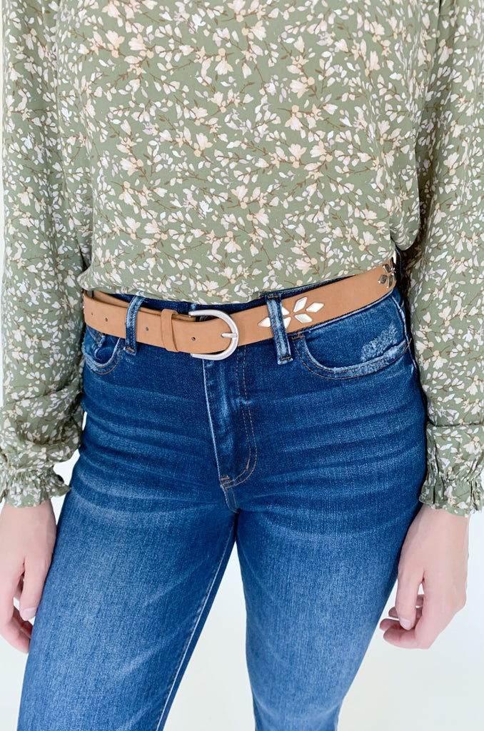 The Tan Belt with Silver Western Embellishments is 43" long. It is a faux leather belt with silver geometric studs. The design creates a floral pattern that is so unique! 