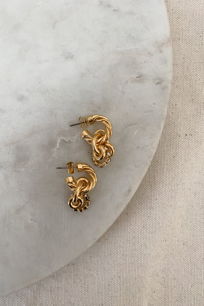 The Twisted Chunky Metal Earrings are so unique! The stud back connects to a larger twisted hoop. Below, there are 3 additional circle charms, two gold, and one rhinestone, connected to another loop. It is intricate and so beautiful! 
