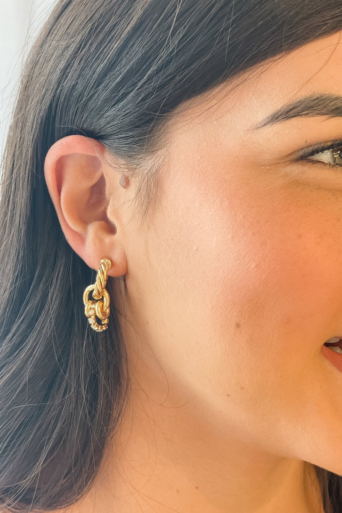 The Twisted Chunky Metal Earrings are so unique! The stud back connects to a larger twisted hoop. Below, there are 3 additional circle charms, two gold, and one rhinestone, connected to another loop. It is intricate and so beautiful! 