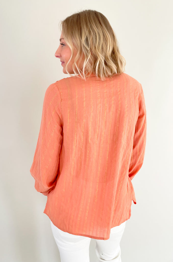 Snag this blouse for a pretty in peach look! It's lightweight, elevated, and perfect for the new season. Plus, the details are stunning! This v neck blouse has unique pleats along the collar, a button up front, cuffed sleeves, and a flowy body. The silhouette will be flattering on so many body types and comfortable too. We paired it with our Wrenley Wash Utility Pant for a fun contrast! 